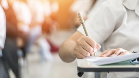 Close up of child writing on exam paper