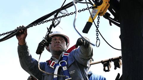 A worker disconnects illegal connections from a power utility pole on August 25, 2013 in Soweto, South Africa.