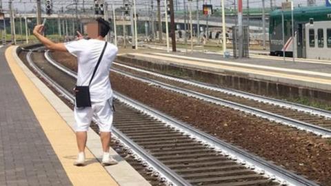 Man takes selfie next to injured person on train tracks