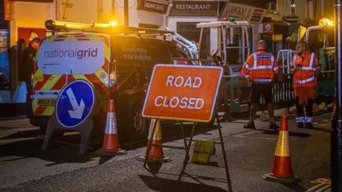 A picture of the scene where a road was closed. A National grid van and workers can be seen.