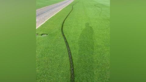 A deep line running across a tennis lawn.
