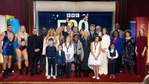 Picture shows: Back: Gladiators Steel and Diamond, Rob Eckland, Paterson Joseph, Marisha Wallace, Sara Cox, Big Zuu, Bradley Walsh, Joanna Page, Barney Walsh, Jodie Whittaker, Her Majesty The Queen, Roman Kemp, Charlie Higson, Alex Jones, Malorie Blackman, Lenny Henry, Francesca Simon, Rose Ayling-Ellis. Front: BBC 500 Words 2026 winners Harry Hart, Zuren Zhang, Ariadne Elena Livas, Annalise Ikeasomba, Maya Ukwubiwe, Muhammed-Da’oud Khan. 