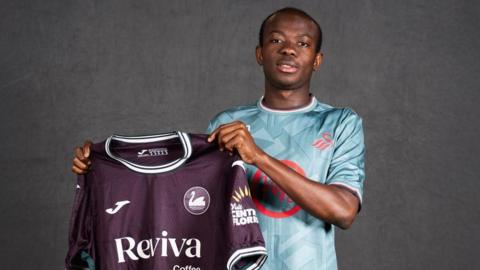 Malick Yalcouye holds up Swansea's away shirt 