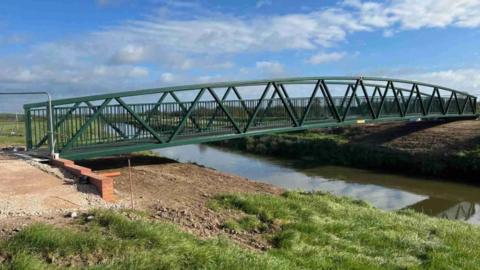 A green metal bridge over a river. 