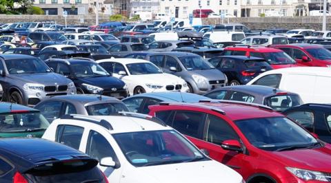 Dozens of cars of various sizes and colours parked in a car park. 