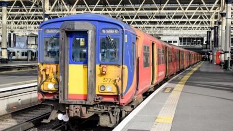 A Class 455 train from the front on the platform of  London Waterloo in South Western Railway livery of blue, yellow and red in 2025 