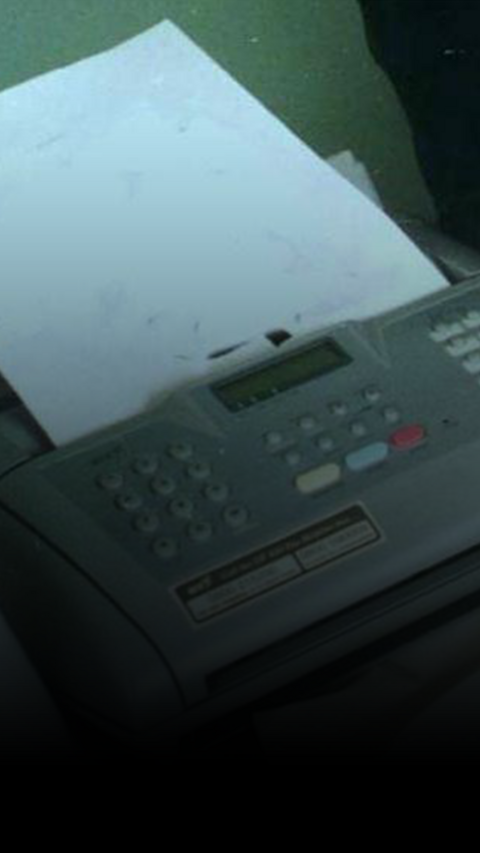 A silver fax machine with kys on the top and paper coming out of it