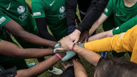 A close up of anonymous footballers forming a huddle before their game 
