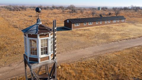 A watch tower in front of a building at the Amache National Historic Site