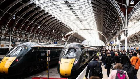 Two GWR trains are parked in a station. There are a lot of people on the platform.