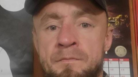 Piotr Pruszak has a light brown beard and wears a cap.