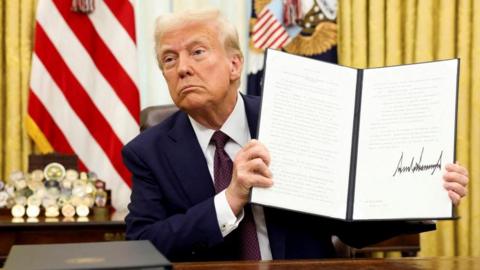 U.S. President Donald Trump holds a signed executive order on AI, in the Oval Office of the White House, in Washington, U.S., January 23,