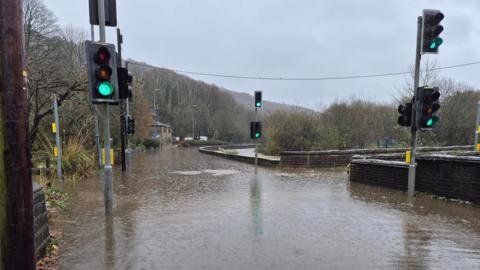 Flooding around a junction between a bridge and a road with traffic lights sticking out of the water.