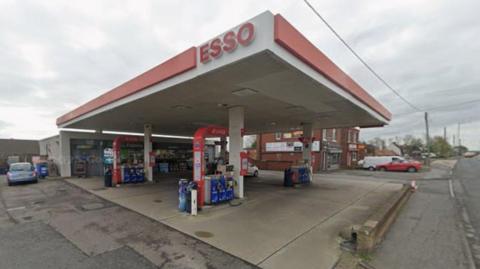 The New Seaham Service Station on Stockton Road. It is an Esso petrol station which is covered with a red and white roof. A small shop stands behind it.