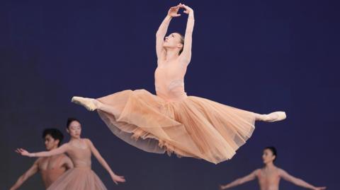 Members of the Birmingham Royal Ballet performing on the Pyramid Stage, at the Glastonbury Festival. Ballerinas are dressed in peach tutu dresses.