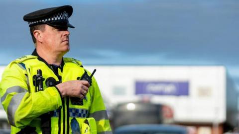 Police officer in high vis police uniform looking on with blurred background.