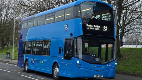 Preston Bus has two shades of blue and is driving past a grass verge
