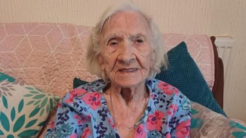 100 year old Betty Atkins sits on a sofa at her home in Paulsgrove