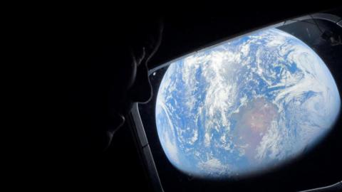 Nasa astronaut looks out of one of the Orion spacecraft's main cabin windows at Earth