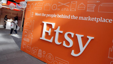 A large Etsy sign shows the company logo written in white letters on an orange background. It includes the slogan: Meet the people behind the marketplace.