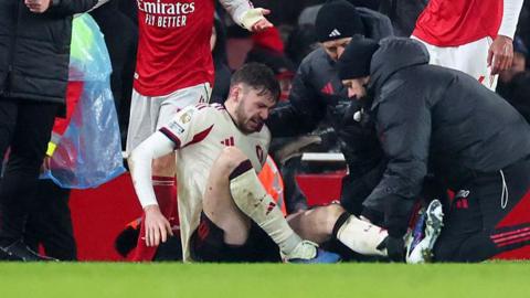 Liverpool defender Conor Bradley is treated for injury on a football pitch