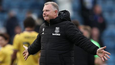 Stoke City manager Mark Robins celebrates in front of the club's fans after beating Portsmouth