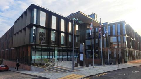An external view of One Angel Square, the modern glass fronted headquarters of West Northamptonshire Council.
