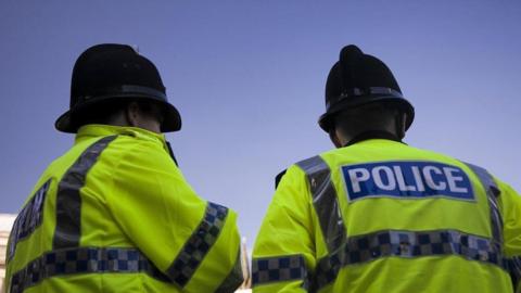 Two police officers facing away from the camera 