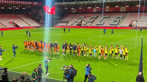 AFC Bournemouth Women and Oxford United Women line up to shake hands on the pitch at the Vitality stadium.