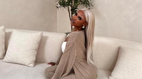 A woman with blonde hair sitting on a white sofa