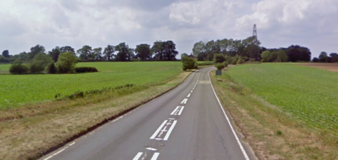 A Google Street View image of B1062 heading in the direction of Bungay from Beccles. The image is made up of a two-lane B-road which is flanked by green farmland with trees in the distance.