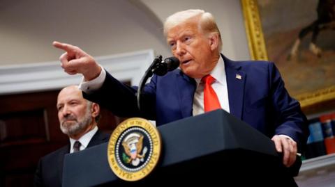 Trump points a finger at a press conference in which he says he will move forward with tariffs