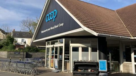 A Coop store from the outside with trolleys parked at the entrance.