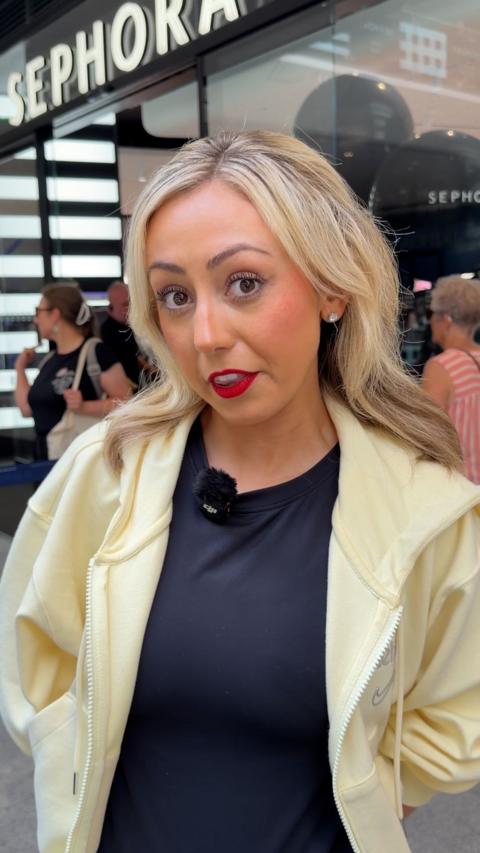 Young woman with blonde hair and red lipstick standing outside a Sephora make up shop