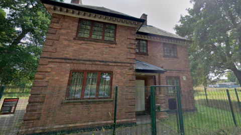 A two storey building next to the entrance to a park