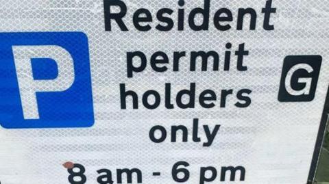A close-up of a parking sign, informing permit holders they can park between 08:00 and 18:00 daily.