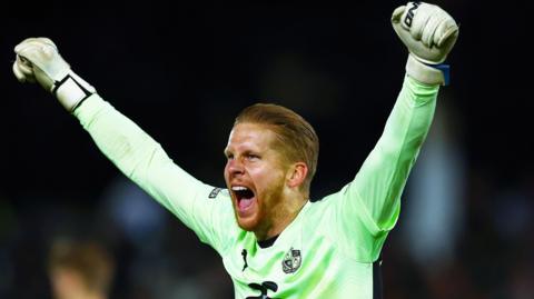 Port Vale goalkeeper Ben Amos throws his arms in the air in celebration and shouts for joy after a win