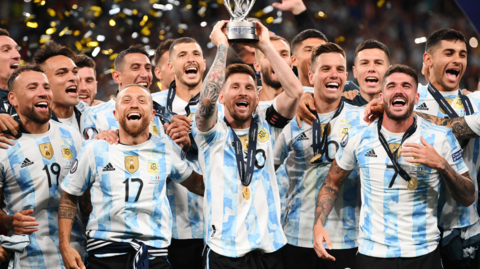 Lionel Messi holds the Finalissima trophy surrounded by Argentina team-mates