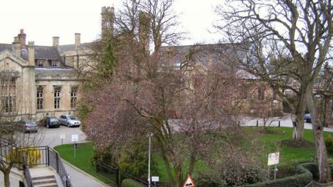 A large stone building with a lawn and trees in front of it.