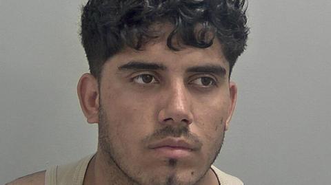 Mugshot of Ahmed Mulakhil, wearing a beige vest.