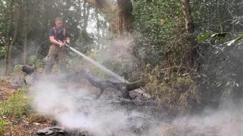 Firefighter tackling a blaze in a woodland