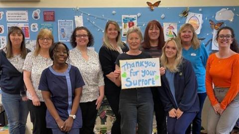 GP with her staff as she holds a "thank you for your support" sign