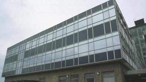 Gloucester Magistrates' Court seen from the outside. The building is grey with many windows across it and is over three storeys