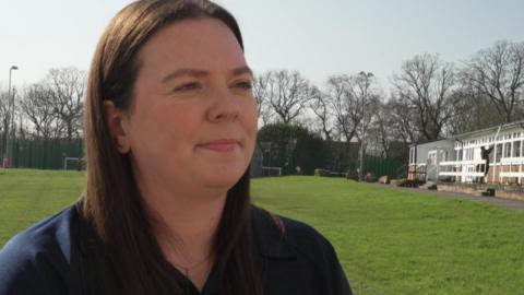 Lisa McCormick, a woman in a blue t shirt with long dark hair, standing on a football pitch