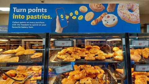 The pastry section at Lidl, with a sign above it saying "turn points into pastries"
