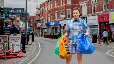 Rachael Clerke stands in a high street carrying shopping bags.