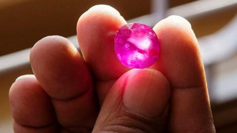 A man shows a roughly polished ruby stone (archive photo)