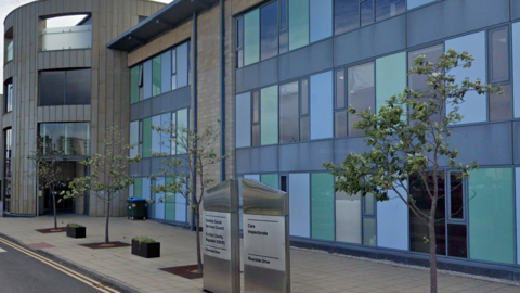 A large office building, with large signs outside it listing what businesses and groups are based there