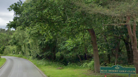 A country road, with a sign saying Beau Desert Golf Club to the right of the picture