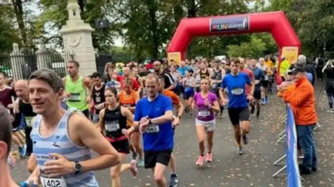 A stream of runners heading away from the starting line in Victoria Park